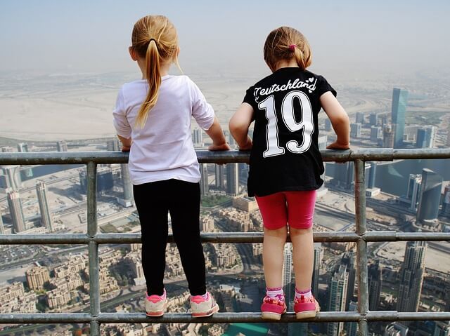 Two children standing on the railing looking at Dubai from a high