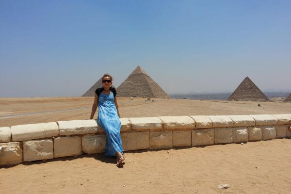 A sitting woman with the Great Pyramids of Giza in the background