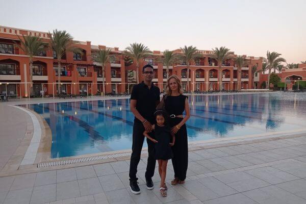 A family of three standing by the pool at Jaz Tamerina Beach Resort in Egypt in the evening.