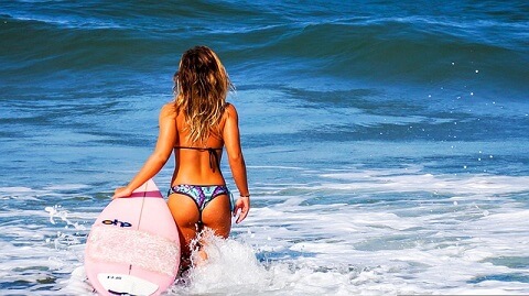 Woman in a bikini with surf in the sea