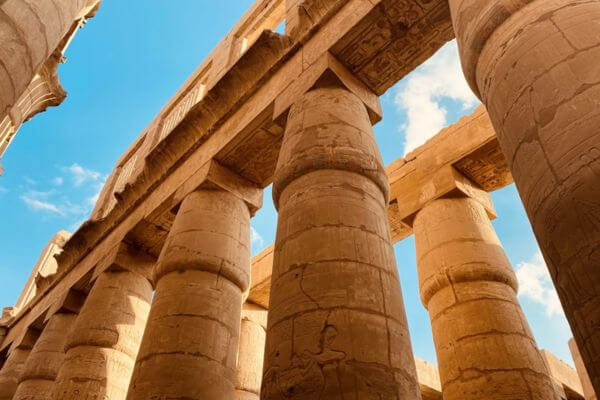 Tall stone columns with hieroglyphic carvings at Karnak Temple in Luxor, Egypt.