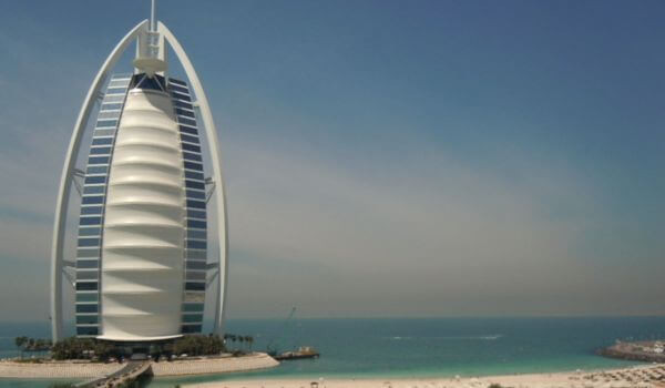 Burj Al Arab Hotel, Dubai The Burj Al Arab Hotel in Dubai stands on its own island, shaped like a sail and surrounded by the calm blue sea. The sandy beach in the foreground leads to the hotel’s private bridge connecting it to the mainland.