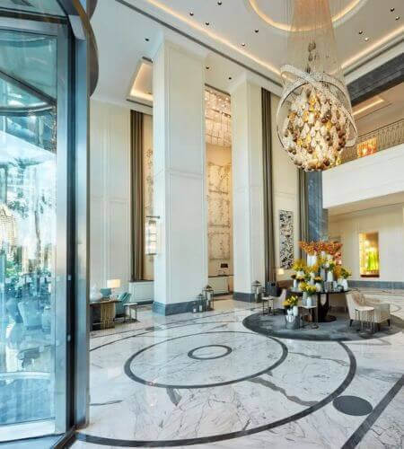 Entrance to Address Boulevard Luxurious lobby at Kempinski The Boulevard Dubai, with marble floors, grand chandelier, and tall windows. Elegant seating area and decorative floral arrangements create an opulent atmosphere.