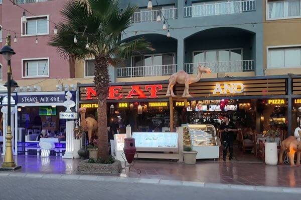 Restaurants in Hurghada, Egypt Restaurants along the street in Hurghada, Egypt, with lit signs, camel statues on the roof, and outdoor seating in the evening.