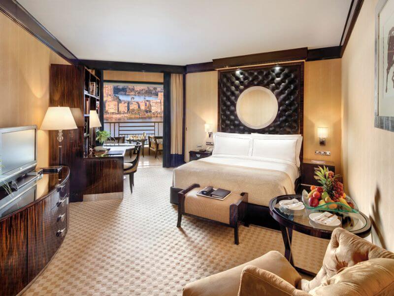 Room at the Fairmont Nile City in Cairo, with a king bed, a small sitting area, and a Nile River view through the window.