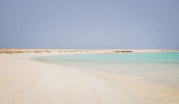 Beach in Marsa Alam, Egypt Tranquil beach scene in Marsa Alam, Egypt with smooth, pale sand curving along a calm, turquoise sea under a clear blue sky; evokes peace and solitude.
