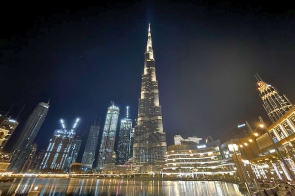 Burj Khalifa, Dubai The Burj Khalifa stands tall against the night sky in Dubai, surrounded by glowing city lights and reflections on the water below. The scene captures the tower’s height and the lively atmosphere of the nearby buildings.
