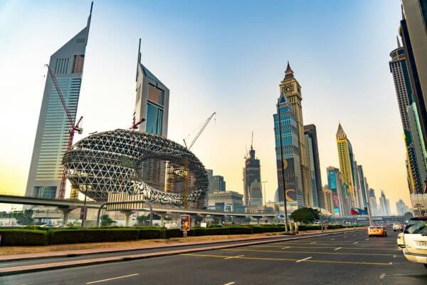 A modern cityscape at dusk featuring the Museum of the Future and towering skyscrapers in Dubai, their silhouettes against a clear evening sky.