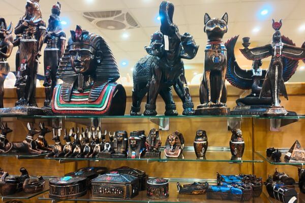 Egyptian souvenir sculptures on display in a shop, including pharaoh busts, cat figurines and Anubis statues.