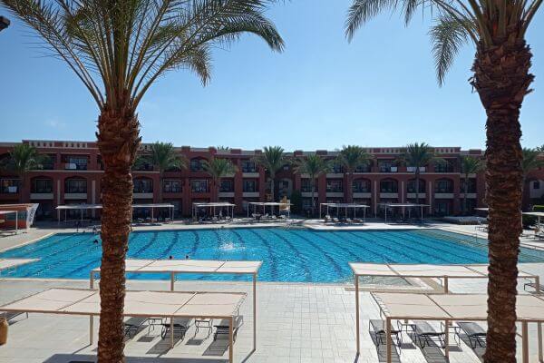 Jaz Tamerina, view of the pool View of the large swimming pool at Jaz Tamerina Hotel, seen from a room balcony. Sunbeds and palm trees surround the pool, with the hotel building in the background.