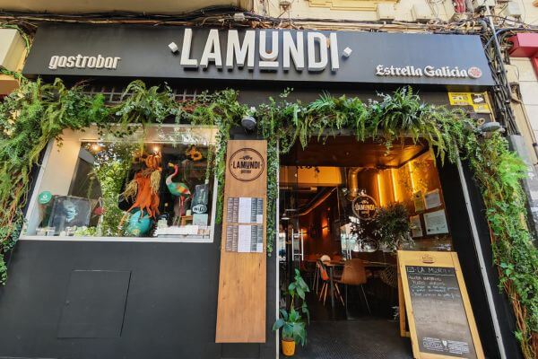 LaMundi Restaurant, Cordoba Entrance to LaMundi gastrobar restaurant in Cordoba with green plants decorating the storefront, menu boards outside, and a warm interior visible through the open doors