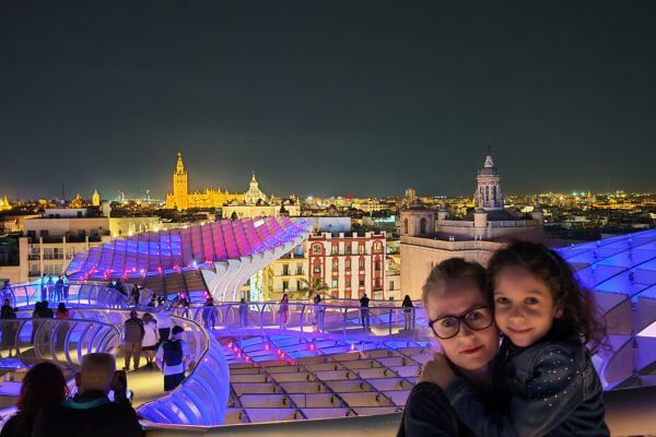 Las Setas, Seville Mother and daughter at the top of Las Setas (Metropol Parasol) in Seville at night with purple light show on the wooden structure and city skyline with lit cathedral in the background