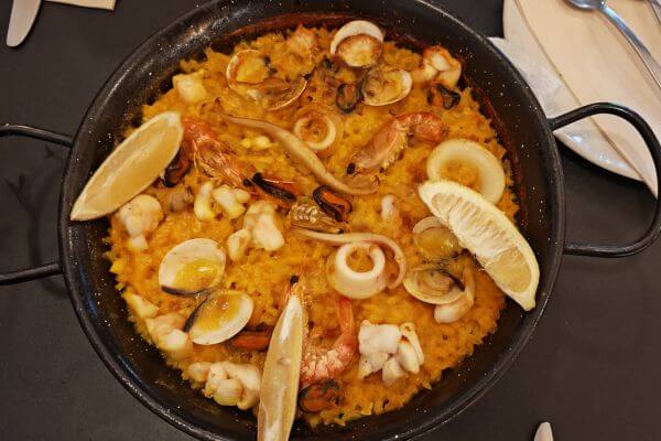 Paella in Senora Pan Restaurant, Seville Seafood paella in a black pan with shrimp, mussels, clams, squid, and lemon wedges on yellow saffron rice at Señora Pan Restaurant in Seville