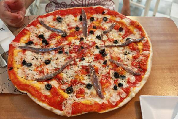 Pizza with anchovies, black olives, cheese, and tomato sauce at DaVinci restaurant in Ronda, Spain.