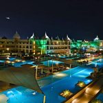 The pools and hotel buildings of Titanic Royal Resort in Hurghada, Egypt, lit up at night.