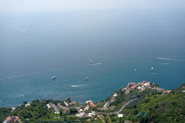 Amalfi Coast by private transfer A view of the Amalfi Coast and the sea from Ravello, Italy, with boats on the water and hillside buildings below.