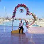 A family posing by a flower arch at Hurghada Marina in Egypt, with boats and yachts in the background.